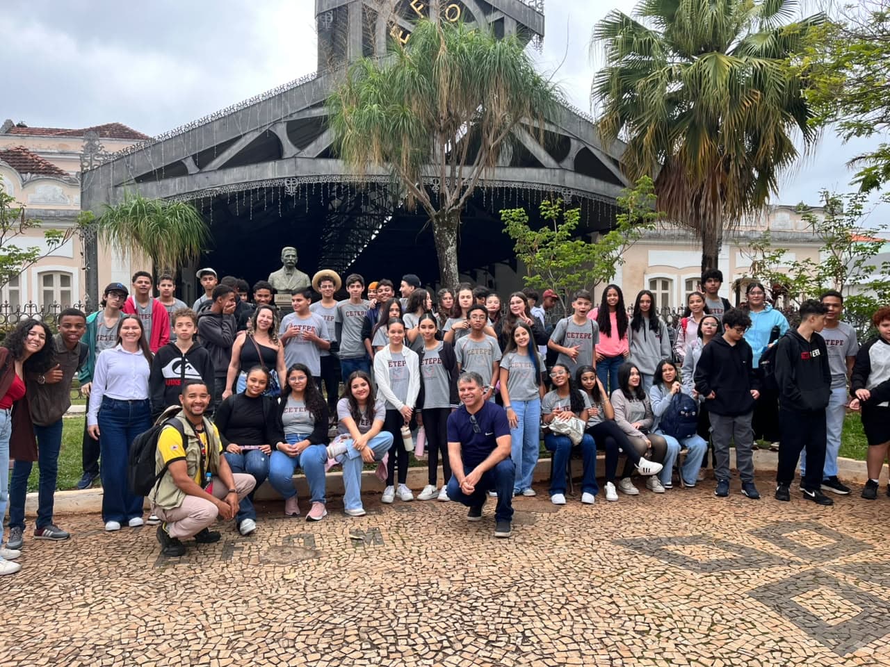 Grupo de estudiantes reunido frente a una estación histórica con palmeras