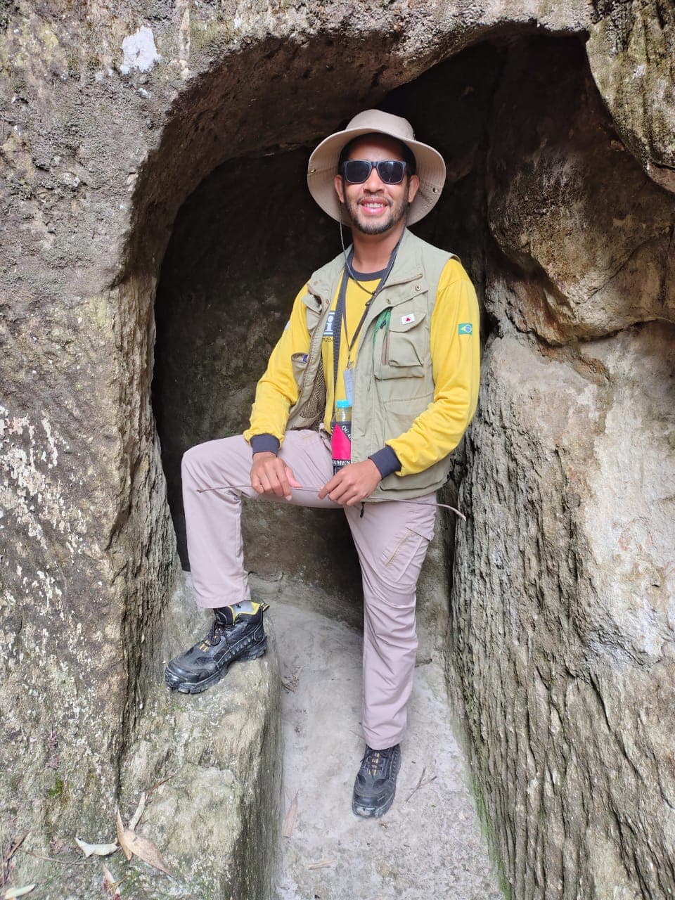Prudêncio con sombrero y gafas de sol, sentado en un nicho de piedra